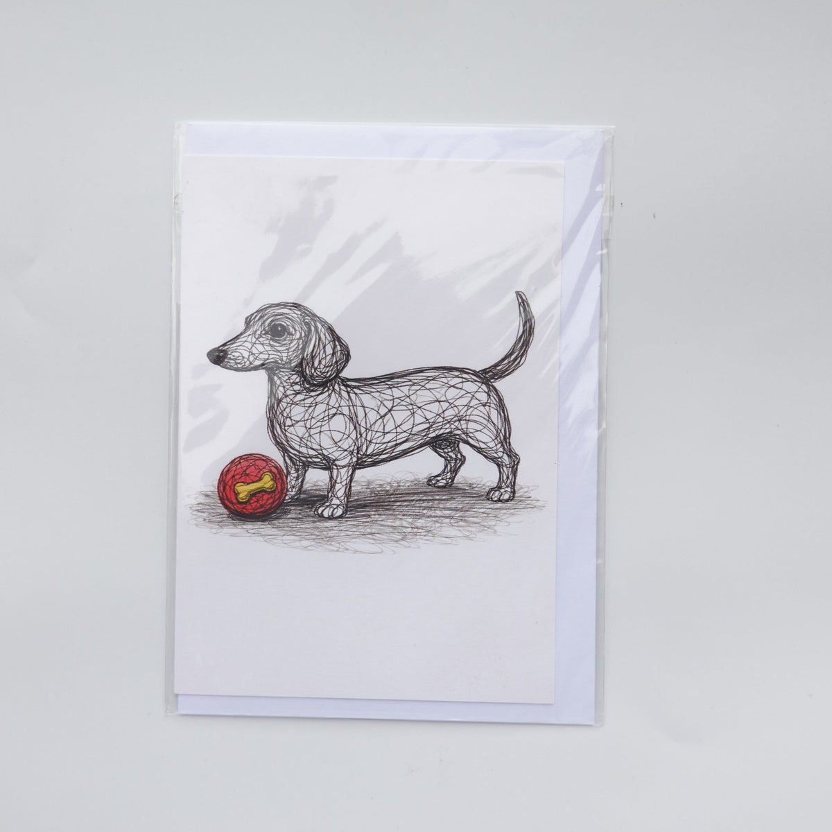 Illustrated Dachshund greetings card with a red ball and envelope